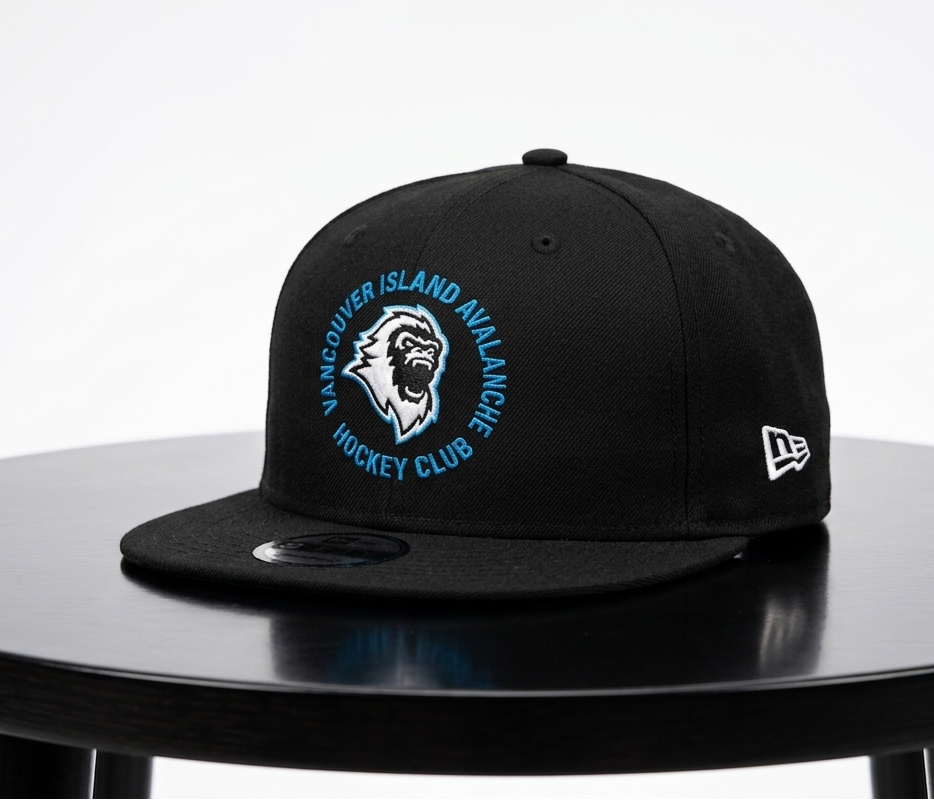 A black Vancouver Island Avalanche hockey club snapback cap by New Era, displayed on a black round table against a light gray background.