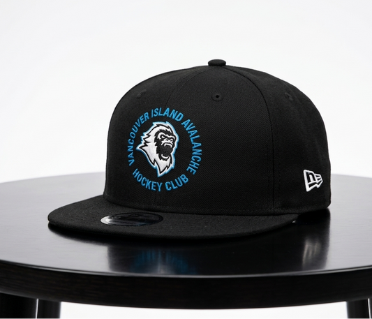 A black Vancouver Island Avalanche hockey club snapback cap by New Era, displayed on a black round table against a light gray background.